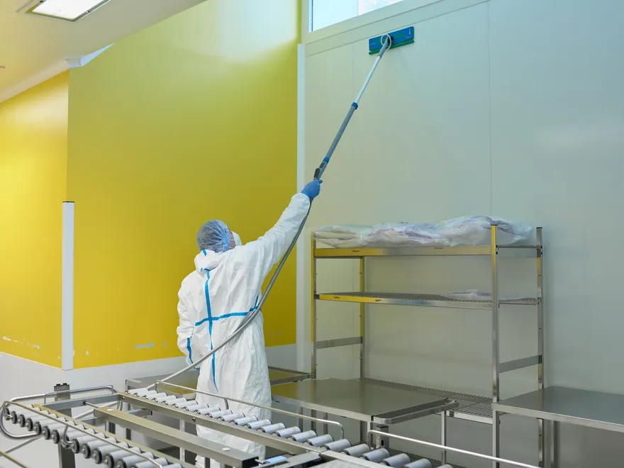 Technicien Eolia en combinaison nettoyant les parois d’une salle